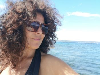 Mature woman wearing sunglasses standing against sea