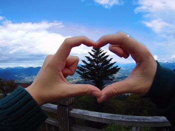 Midsection of woman holding heart shape against tree