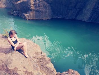 Girl sitting on rock by sea