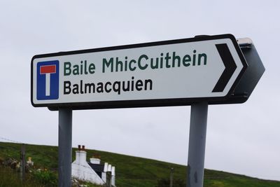 Close-up of road sign against sky