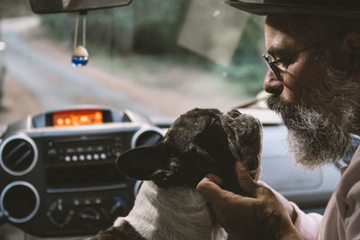 A warmly dressed man enjoying the modern truck with his dog sitting in the driver's seat. traveling