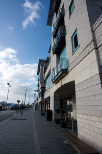 Empty road amidst buildings in city against sky