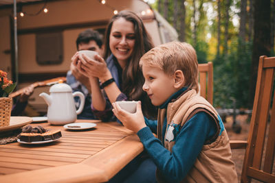 Happy family on camping trip relaxing in the autumn forest camper trailer. fall season outdoors trip