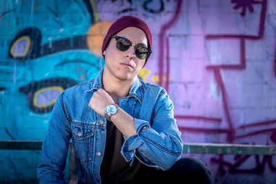 Portrait of young man wearing sunglasses against wall