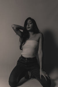 Young woman looking down while sitting against wall