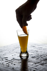 Cropped hand holding orange slice inside juice glass