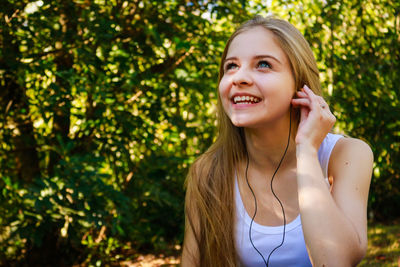 Young woman smiling while listening music at park
