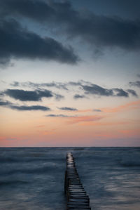 Pier over sea against sky during sunset