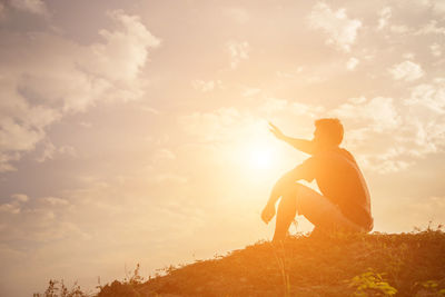 Silhouette man sitting against sky during sunset