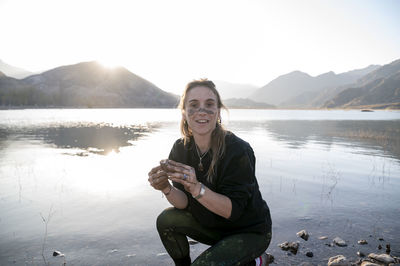 Woman putting mud on hands and face while enjoying outdoors in nature.