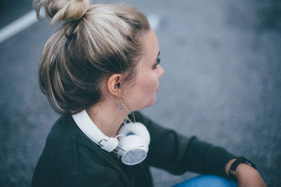 Side view of young woman with headphones sitting on road