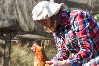 Mature woman with hen at farm