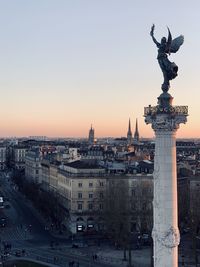 Statue in city against clear sky during sunset
