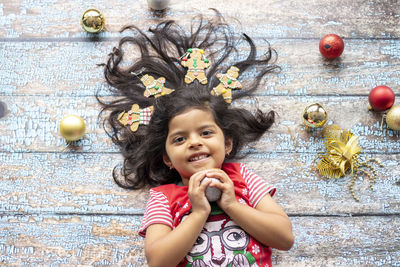 Portrait of smiling girl with christmas ornament on floorboard