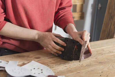 Midsection of woman working over shoe on table in workshop