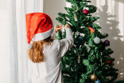 Rear view of girl decorating christmas tree