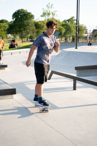 Rear view of young man skateboarding on footpath