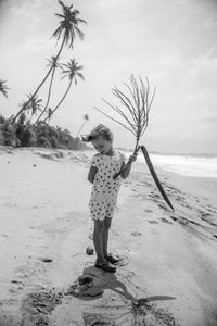 Full length of girl standing on beach against sky