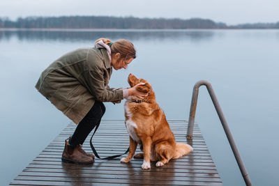 Young woman with dog on pier by lake