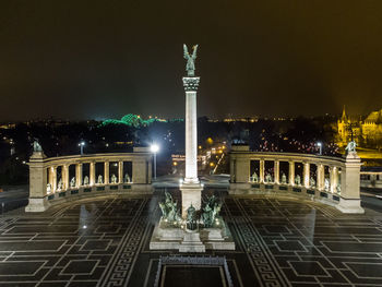 Statue in city against sky at night