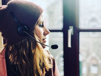 Close-up of young woman wearing headset looking away