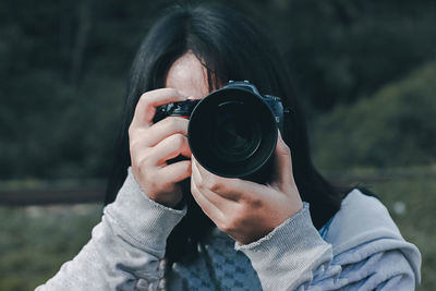 Woman photographing while standing outdoors