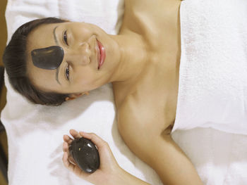 Portrait of woman having lastone therapy while lying on massage table