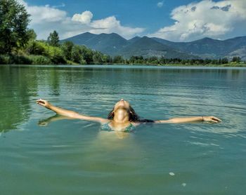 Man swimming in lake against mountain range