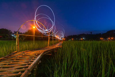 Light trails on field against sky at night