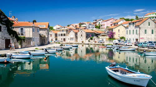 Sailboats moored on canal amidst buildings in city