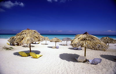 Parasols and chairs at beach against sky