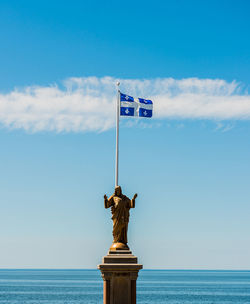Statue by sea against blue sky