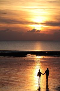 Silhouette mother and daughter walking at beach