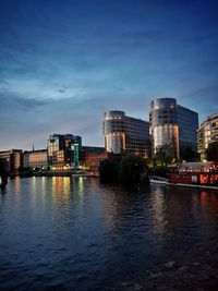 River by buildings against sky at dusk