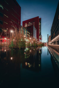 Illuminated bridge over river in city at night