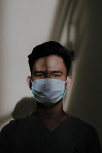 Close-up portrait of young man wearing mask against wall