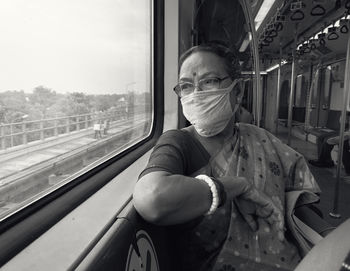 An elegant looking aged bengali woman travelling by kolkata metro rail wearing protective face mask