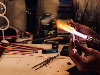 Cropped hands of welder welding equipment at workbench in workshop