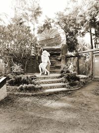 Rear view of two women standing by tree