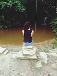 Rear view of woman with arms raised against trees