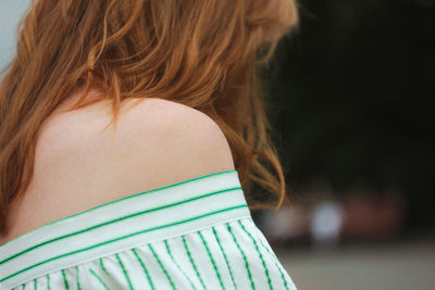 Side view of woman in off shoulder dress sitting outdoors