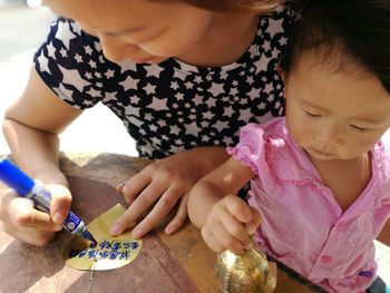 High angle view of woman with little girl writing prayer message