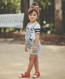 Full length of smiling girl standing against tree