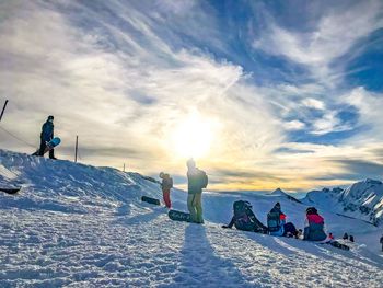 People on snowcapped mountain against sky during winter