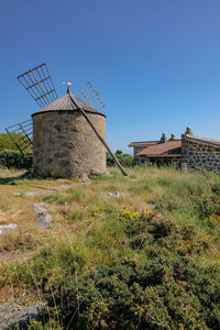 Traditional windmill on field against clear sky