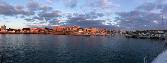 View of buildings by sea against cloudy sky