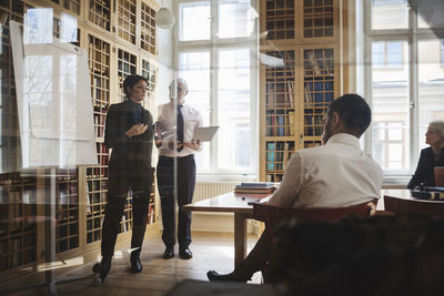 Lawyers giving presentation to coworkers seen through glass in board room