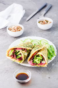 Egg rolls filled with pastrami, vegetables and green onions on a plate, sprouted grains 