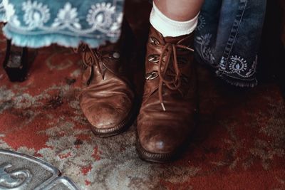 Low section of boy wearing leather shoes on rug