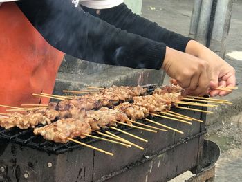 Midsection of man preparing meat on barbecue grill